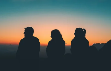 Three people watching a sunset