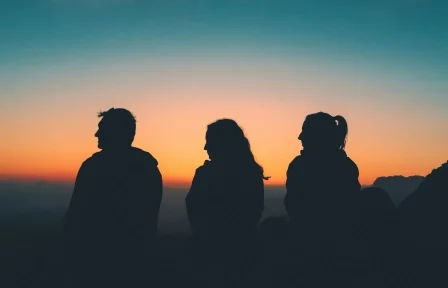 Three people watching a sunset