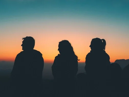 Three people watching a sunset
