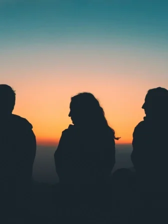 Three people watching a sunset
