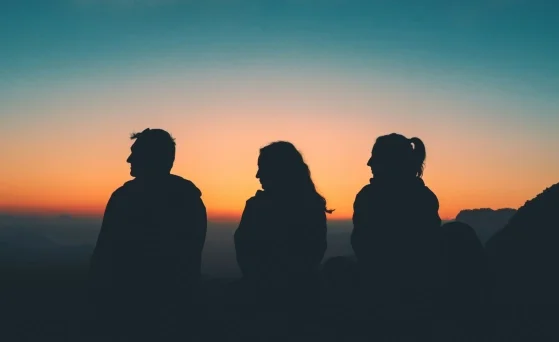 Three people watching a sunset